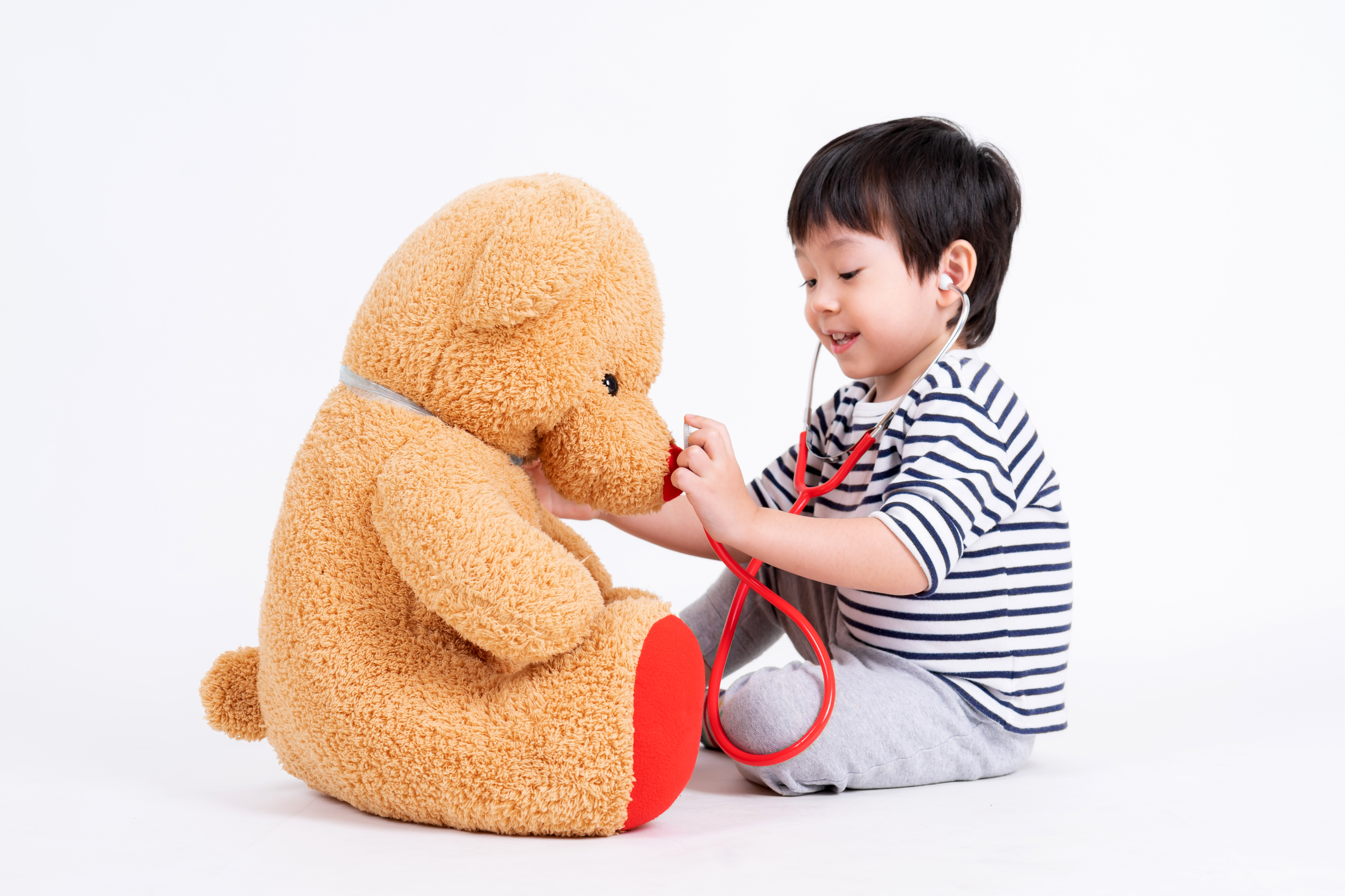 Little boy playing doctor with teddy bear